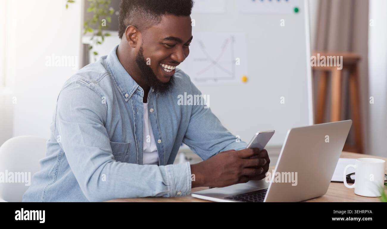 Happy black manager looking at smartphone la lecture à l'écran message agréable Banque D'Images