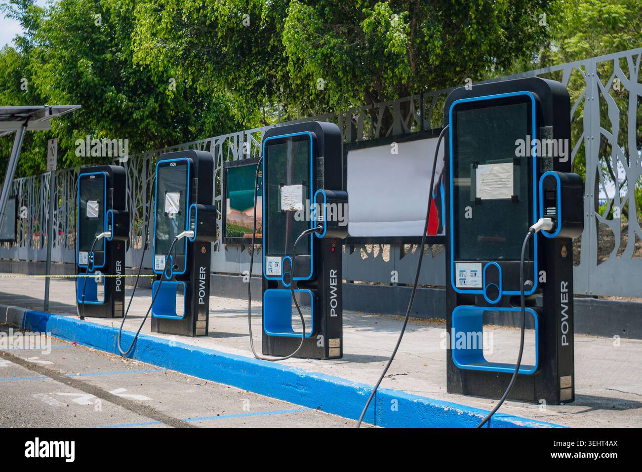 Une rangée de bornes de recharge noires modernes avec des détails bleus se dresse alignée à l'extérieur, prête à alimenter les voitures électriques. Banque D'Images