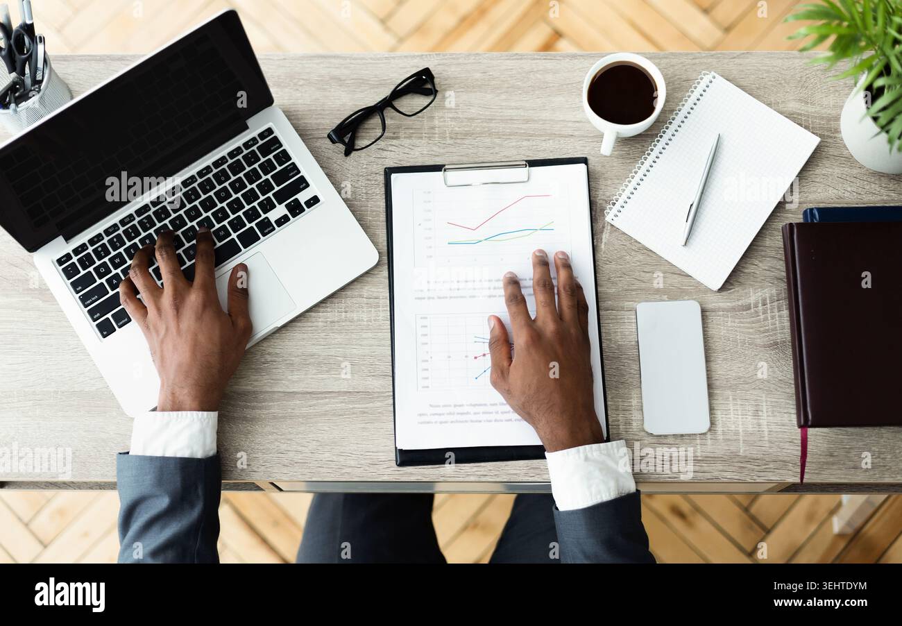 Professionnel de l'entreprise analyser des données sur un ordinateur portable à un bureau en bois dans un bureau moderne Banque D'Images