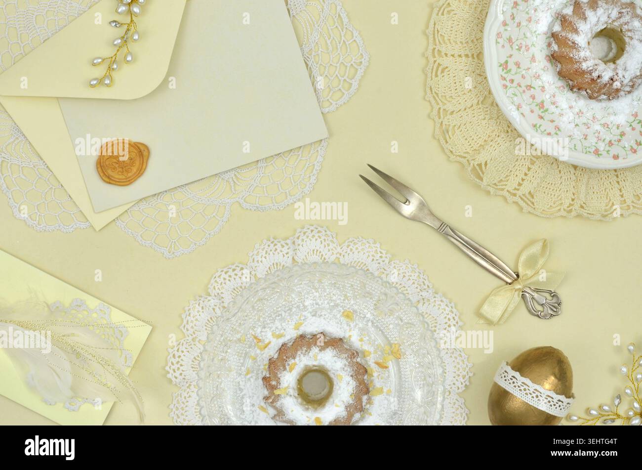 Jaune, couleur unique de Pâques, décoration de table pastel avec des gâteaux de Pâques, oeuf doré, fourchette élégante, une enveloppe et un carton jaune à remplir de contenu. Banque D'Images