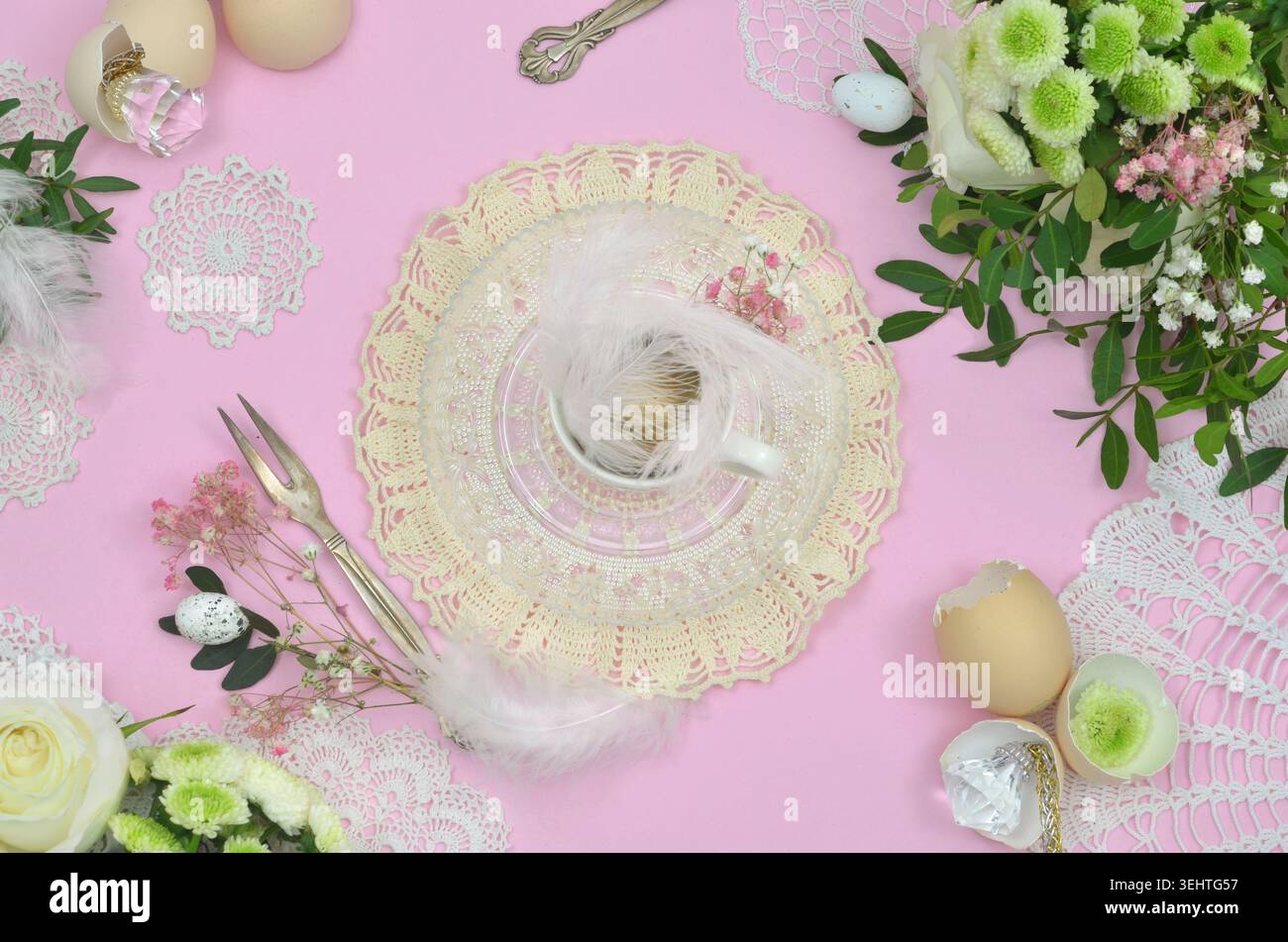 Décoration de table élégante : serviette crochetée jaune, plumes, œufs, fond rose et deux beaux bouquets de fleurs blanches, Pâques. Banque D'Images