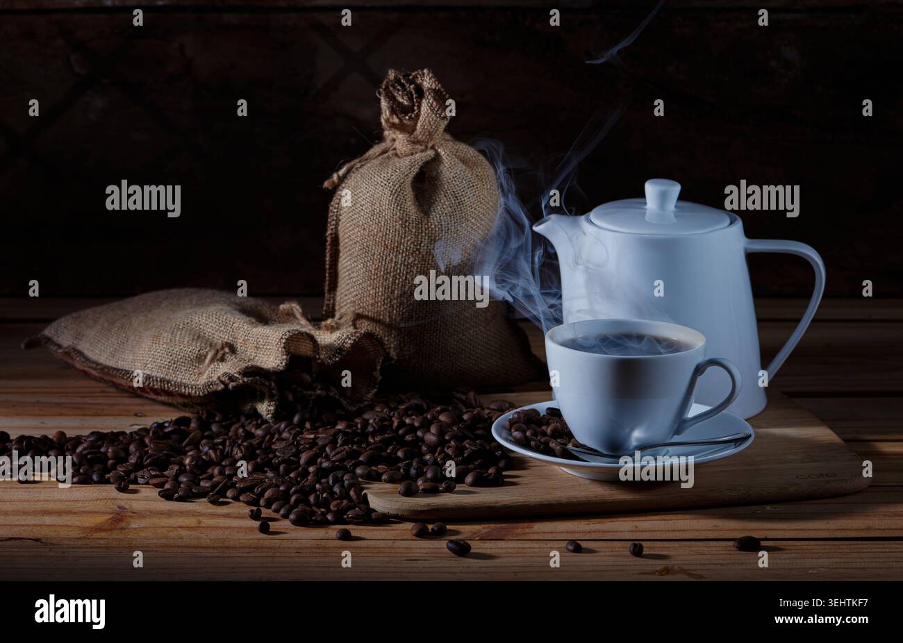 Moody Still Life de café chaud fraîchement préparé servi dans une tasse en céramique blanche et une théière avec vapeur visible. Banque D'Images