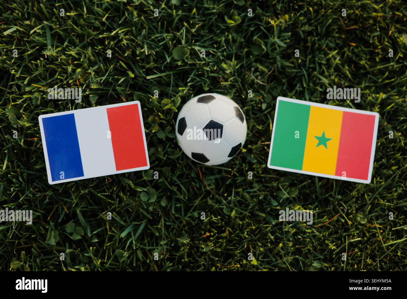 Ballon de football entre la France et le Sénégal drapeaux sur le terrain d'herbe verte. Concept de match de football international, compétition de championnat. Banque D'Images