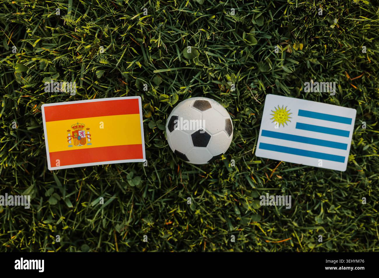 Concept de match de football avec les drapeaux de l'Espagne et de l'Uruguay et un ballon de football sur un terrain en herbe verte. Championnat international. Banque D'Images