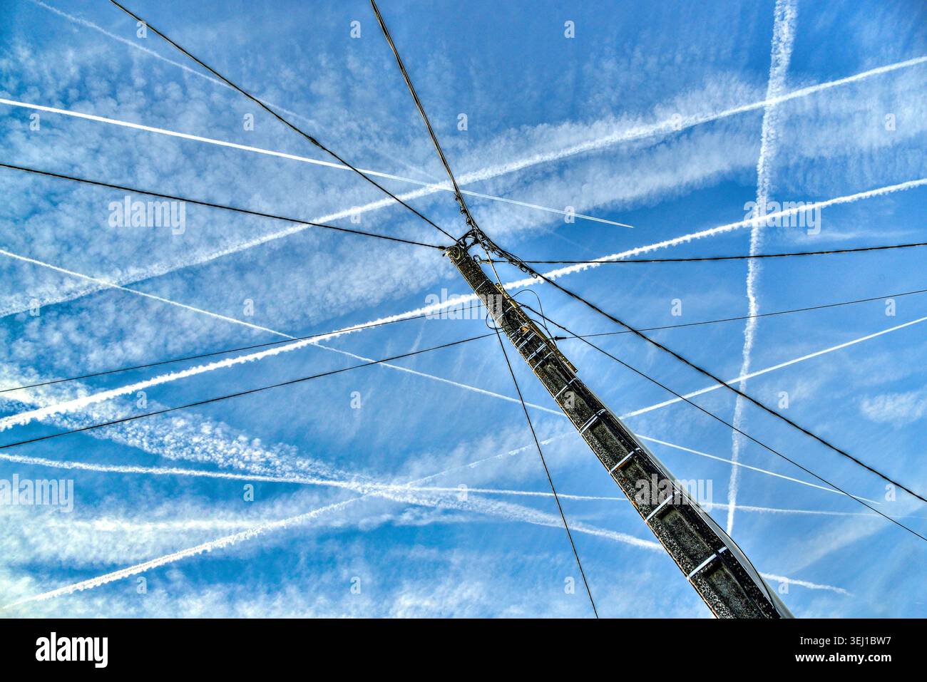 Câbles électriques sur poteau de service et traînées de vapeur tôt le matin au-dessus du centre de la France provenant d'avions à réaction frits vers le sud depuis Paris. Banque D'Images