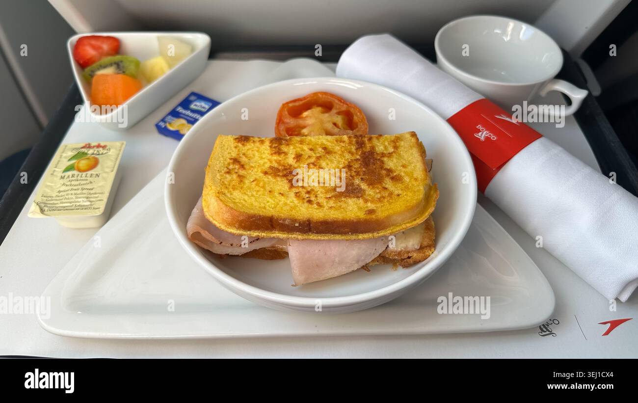 Repas petit-déjeuner servi à bord d'un vol Austrian Airlines avec sandwich chaud, fruits, tasse à café et articles de restauration. Banque D'Images