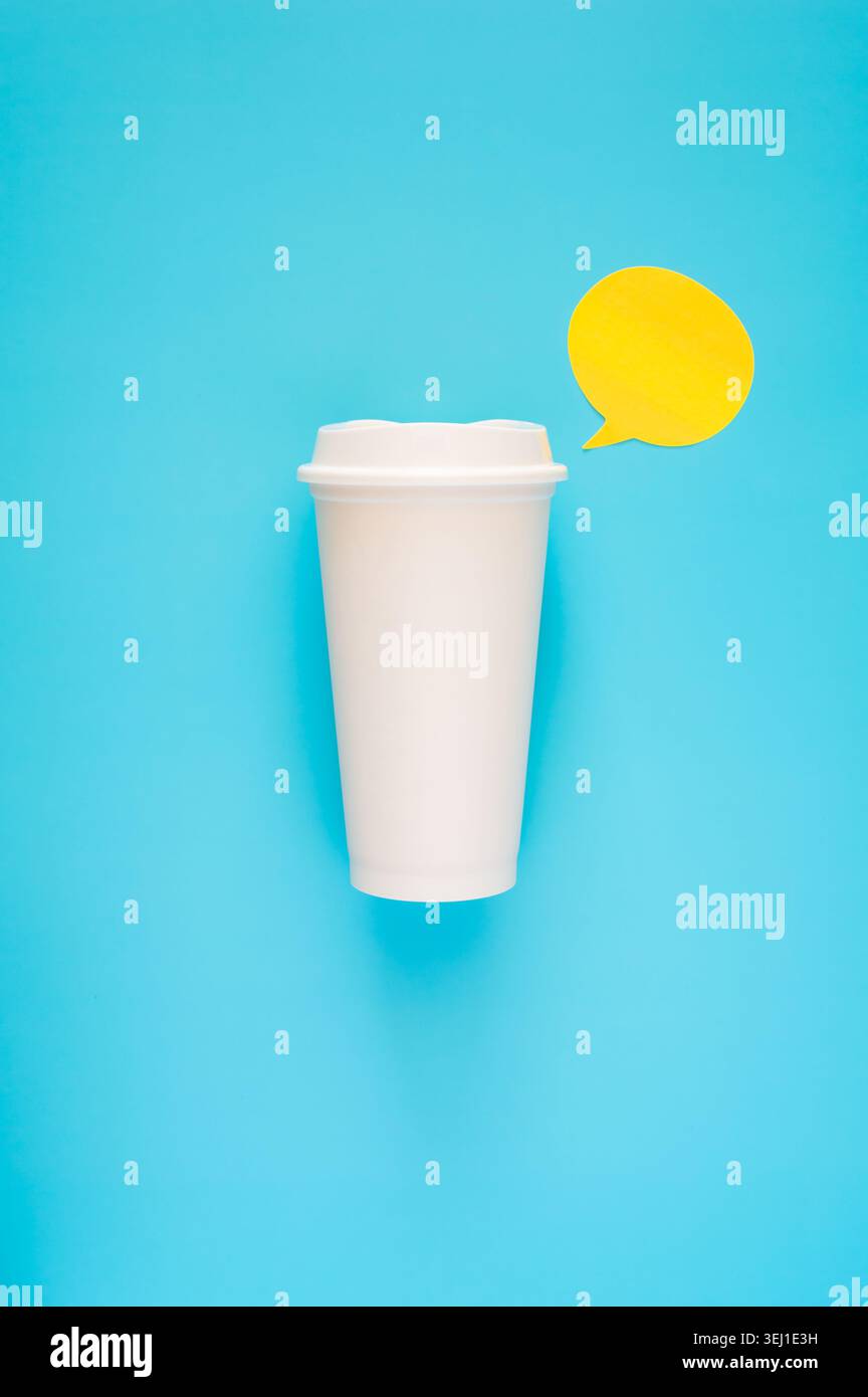 Une tasse à café blanche sur un fond bleu vif accentué par un bloc-notes jaune. Banque D'Images