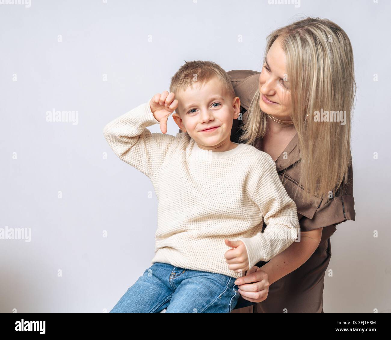 Garçon de 4-5 ans garçon assis sur les genoux de maman maman souriant et regardant le garçon, le garçon montre un doigt vers le bas, à la fois l'apparence européenne blonde de bleu Banque D'Images