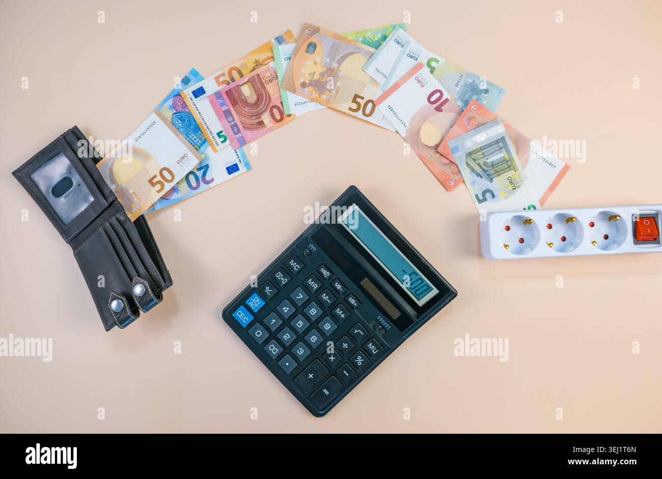 Euros arrangés avec une calculatrice et une rallonge. La scène illustre les factures élevées de services publics et le stress financier. L'argent est visiblement alloué Banque D'Images