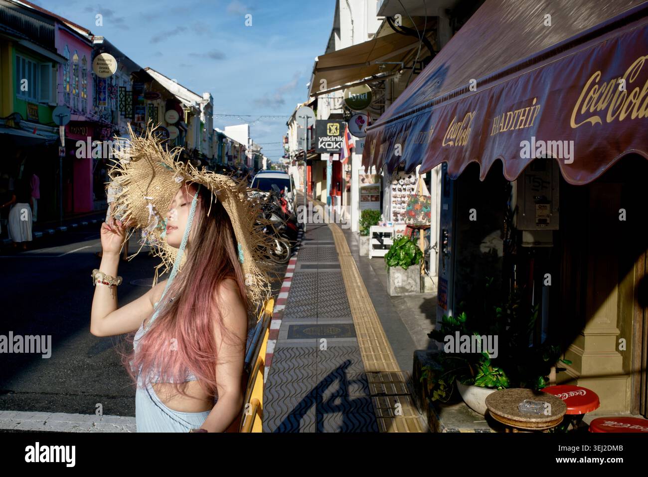Photo franche d'un jeune touriste chinois posant pour un ami (hors caméra) dans la pittoresque route de Thalang dans la vieille ville de Phuket Town, en Thaïlande Banque D'Images