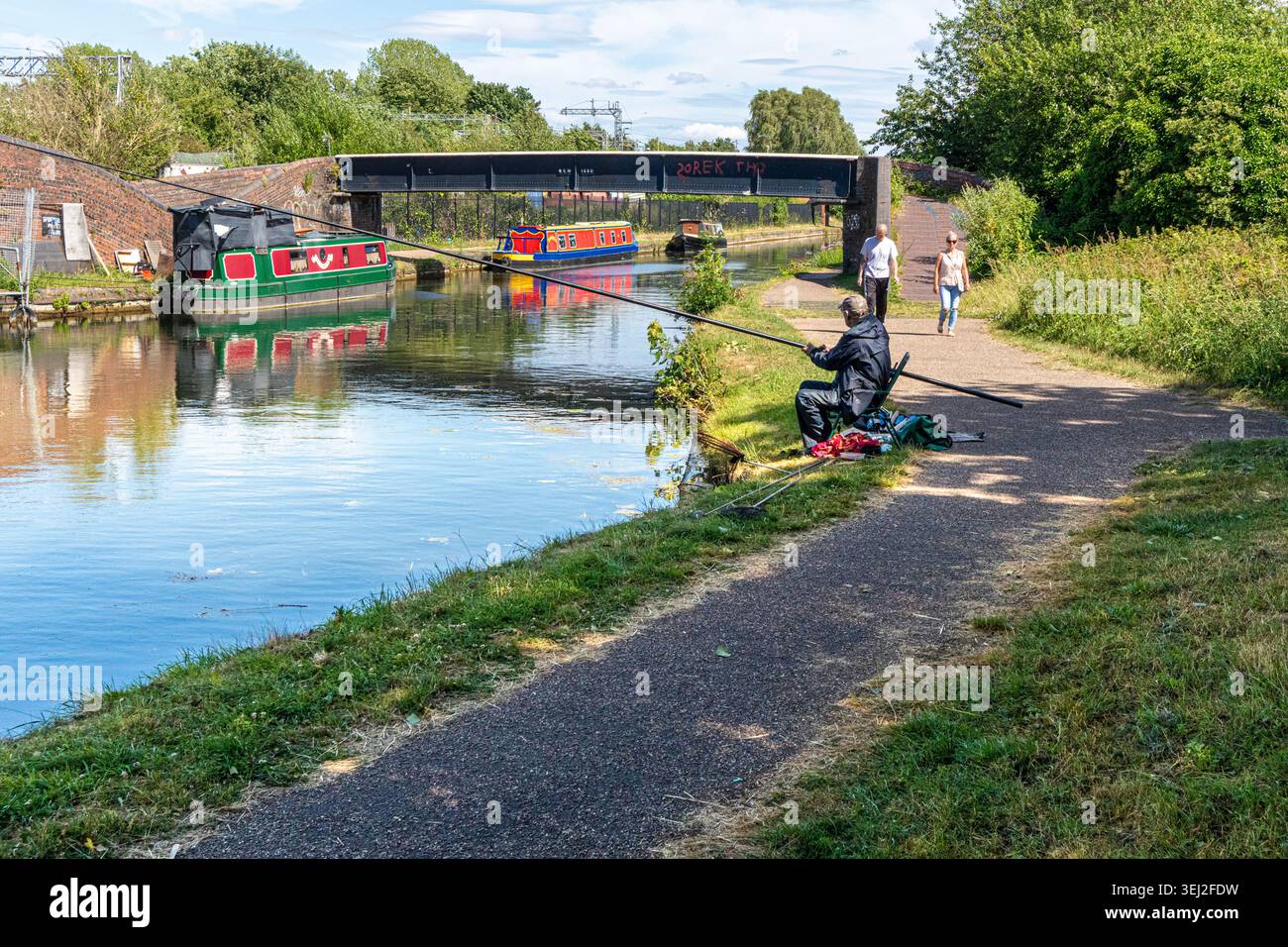 Un pêcheur et des marcheurs sur le chemin de halage du canal Dudley à Old Hill près de Blackheath, West Midlands, Angleterre Royaume-Uni Banque D'Images