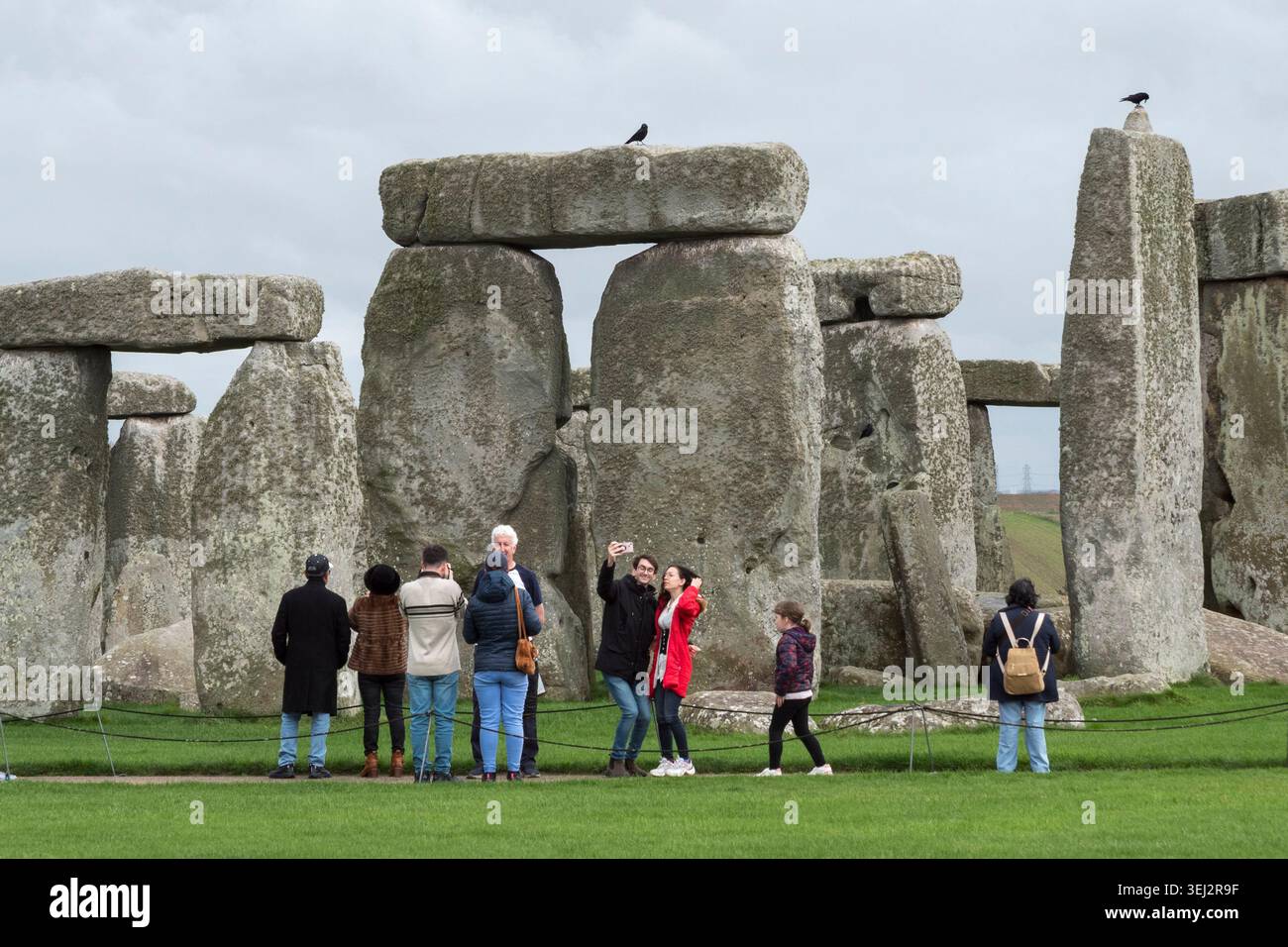 Visiteurs sur le chemin principal observant Stonehenge sur la Salisbury Plain, Wiltshire, Royaume-Uni. Banque D'Images