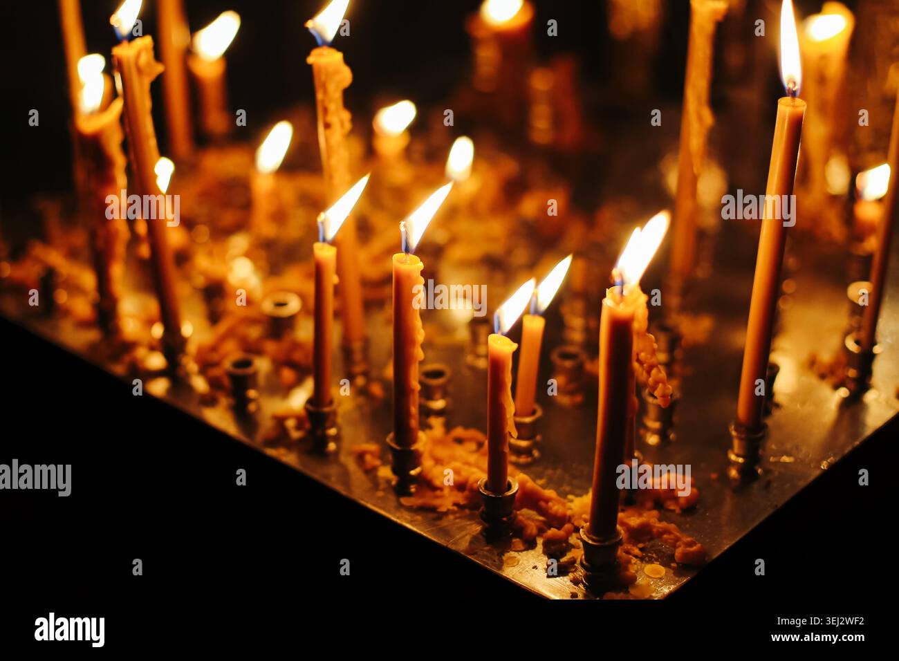 Bougies d'église allumées en gros plan. Foi religieuse et concept de prière spirituelle avec une lumière chaude dans un lieu sacré. Banque D'Images