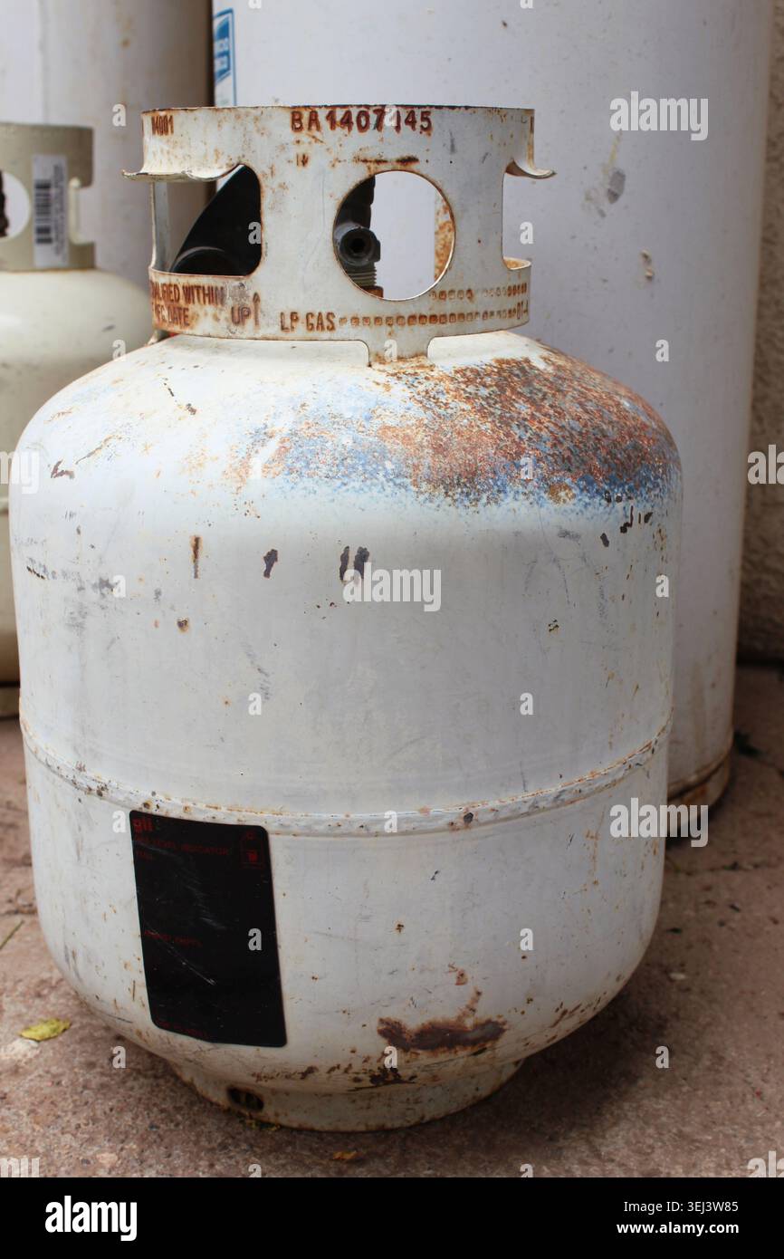 Réservoir de gaz liquéfié blanc rouillé de 9 kg avec son numéro de série gravé, avec d'autres réservoirs flous en arrière-plan. Concept : utilisation domestique du réservoir de gaz liquéfié Banque D'Images