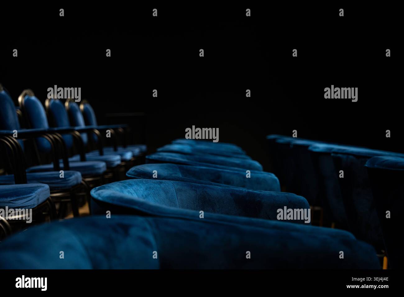 Sièges de cinéma Empty Velvet dans l'obscurité, intérieur de luxe Moody avec rangées en peluche bleu profond, éclairage bas-de-gamme dramatique et indice Spotlight, silencieux Banque D'Images