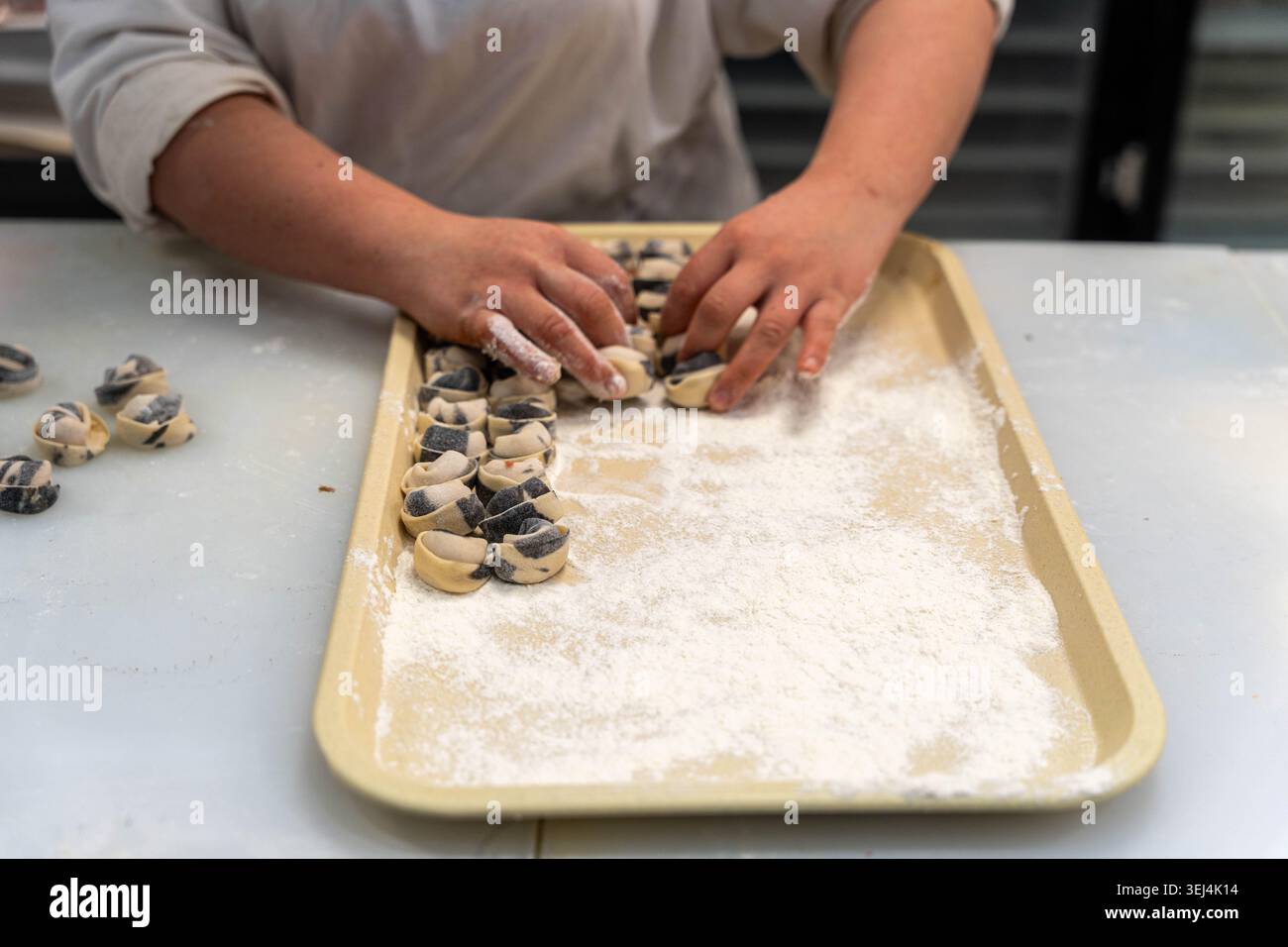 Mains façonnant la pâte à biscuits sur un plateau, surface farinée, Home Baker préparation de biscuits bitumineux, doigts concentrés arrangeant des ronds de chocolat tourbillon, Banque D'Images