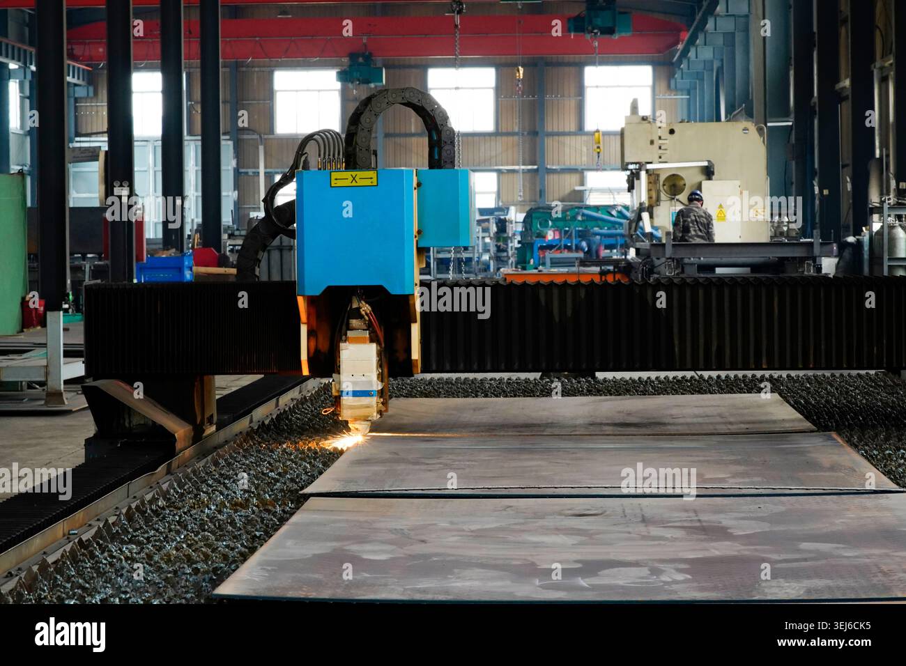 Une machine de découpe laser à fibre optique travaille dans un atelier industriel. Le corps principal de l'équipement est bleu-vert, et la tête de coupe est pro Banque D'Images