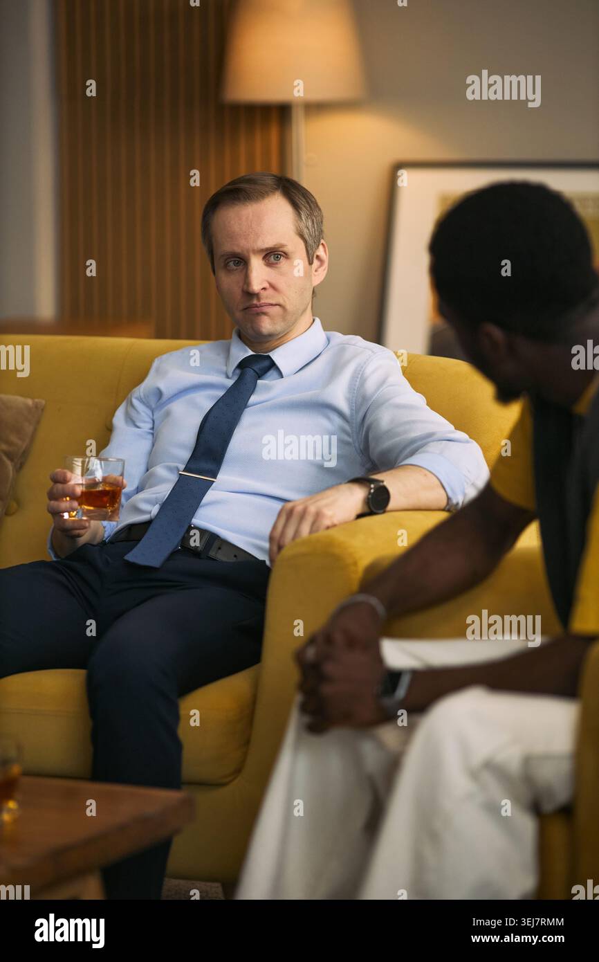 Plan vertical d'un homme caucasien d'âge moyen écoutant Black Friend au cours d'une conversation sérieuse, exprimant confiance et soutien. Idéal pour l'amitié, la santé mentale des hommes, les campagnes de conseil Banque D'Images