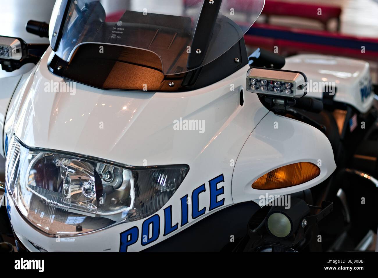 Gros plan d'une moto blanche de police montrant un phare, un pare-brise et un éclairage de secours à l'intérieur. Banque D'Images
