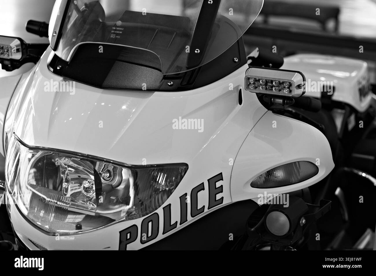 Gros plan d'une moto blanche de police montrant un phare, un pare-brise et un éclairage de secours à l'intérieur. Banque D'Images