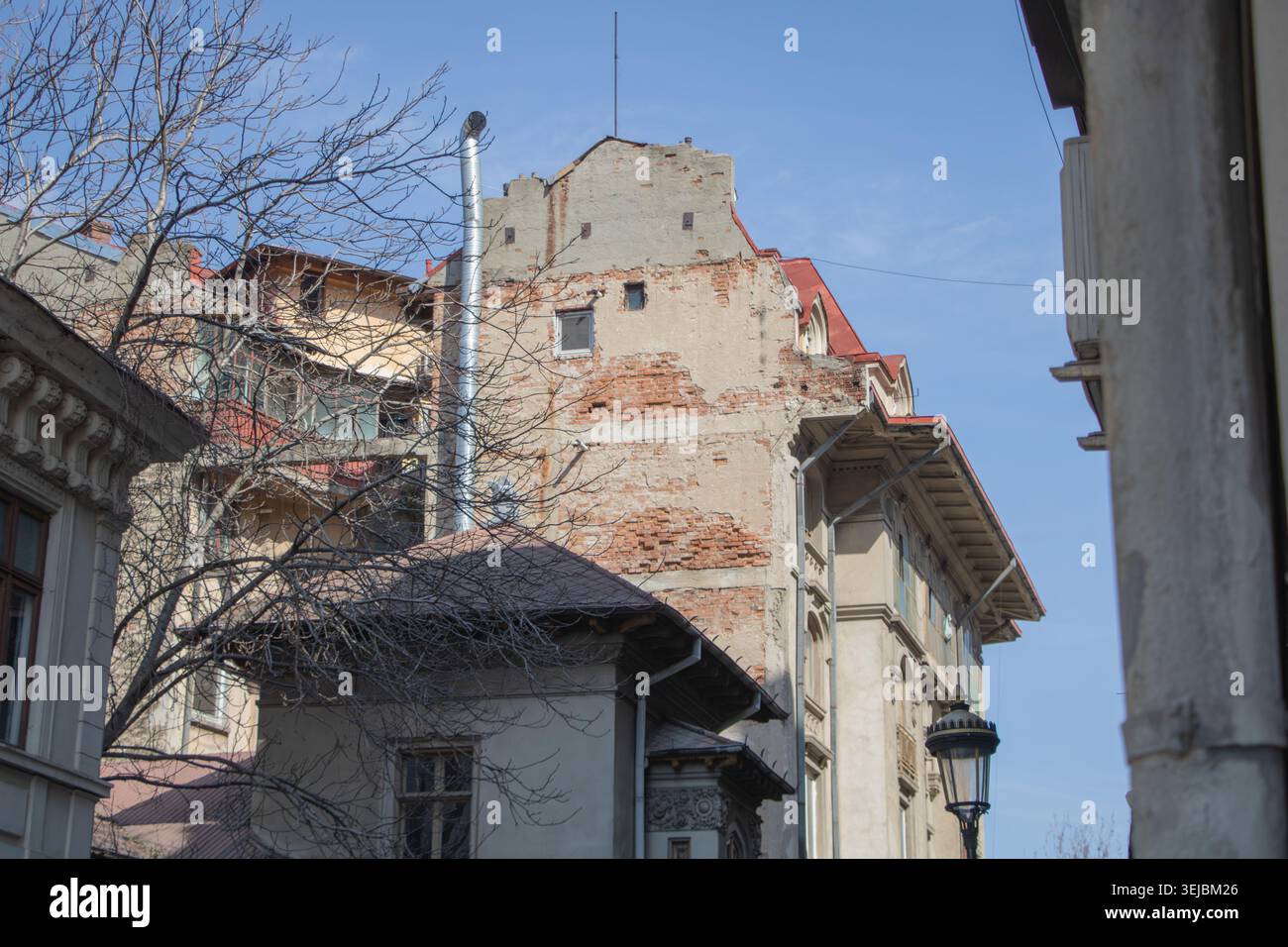 Immeuble résidentiel urbain vieilli avec murs de briques apparentes et façade détériorée entouré d'une architecture historique à Bucarest. Banque D'Images