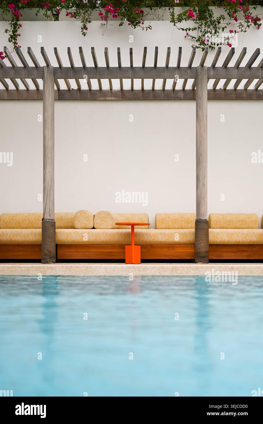 Un coin salon extérieur confortable sous une pergola près d'une piscine. Banque D'Images