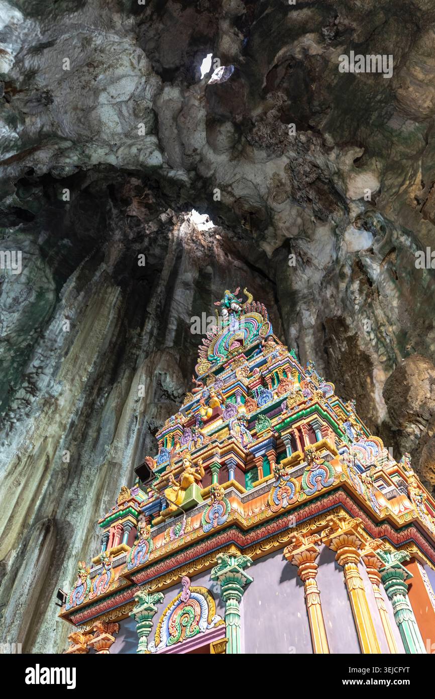 Vue en contre-plongé d'une tour de temple hindou ornée s'élevant vers des ouvertures de lumière naturelle dans le plafond de la grotte de calcaire aux grottes de Batu, Selangor, Malaisie Banque D'Images