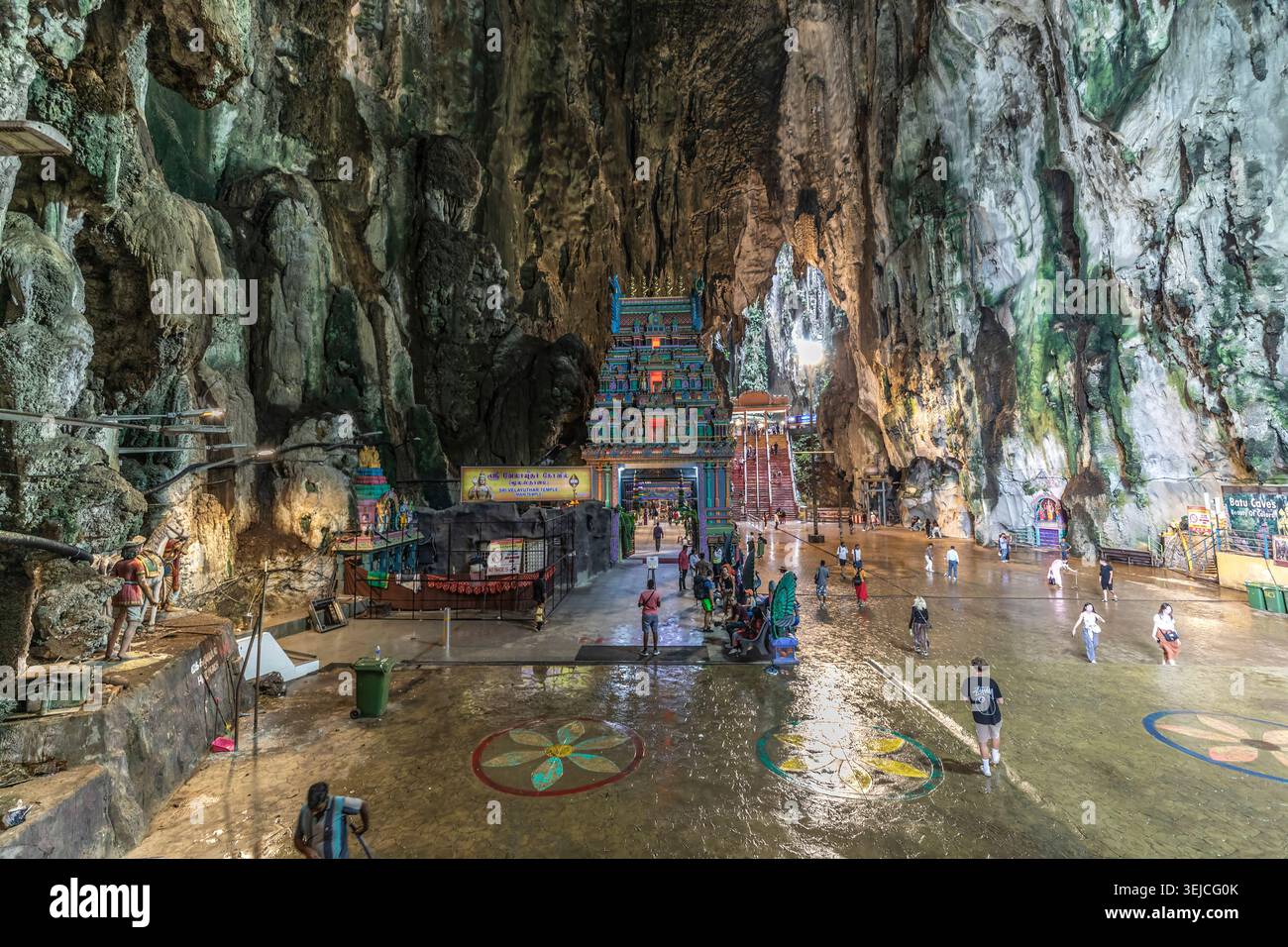 Les touristes traversent le sol de la grotte cathédrale sous les parois rocheuses en direction du temple hindou Sri Velayuthar à l'intérieur des grottes de Batu près de Kuala Lumpur, en Malaisie Banque D'Images