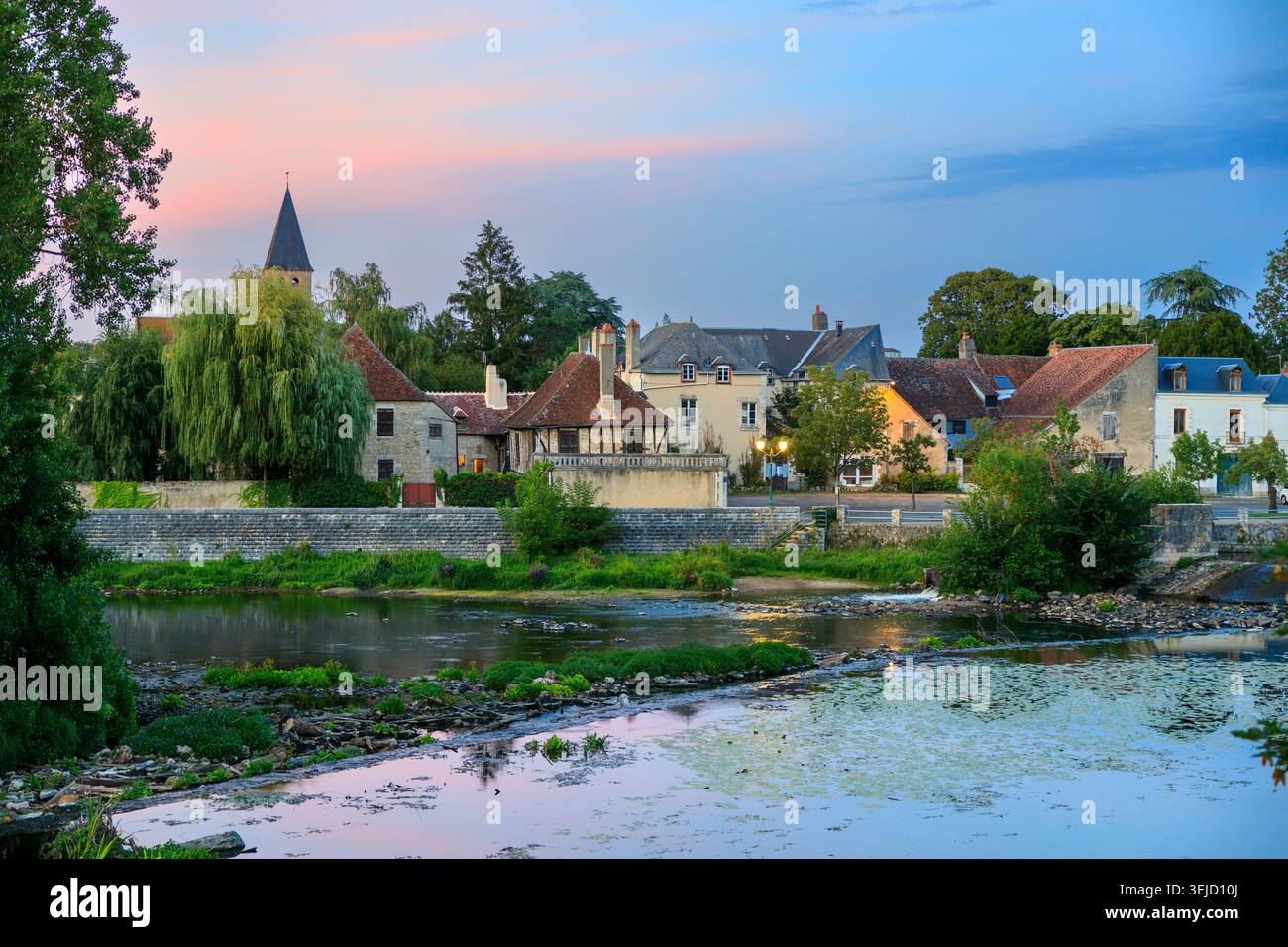 Le Blanc, France - 15.08.2023 : paysages pittoresques au bord de la rivière avec une ancienne architecture française, une végétation luxuriante et une tour d'église au coucher du soleil Banque D'Images