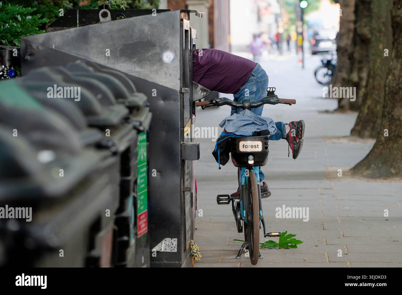 Londres, Angleterre, Royaume-Uni. 29 mai 2026. Un homme fouille dans une poubelle de collection de vêtements tout en se balançant sur un vélo à Westminster, Londres, au milieu des pressions continues sur le coût de la vie et des préoccupations croissantes de sans-abri dans toute la capitale. (Crédit image : © Thomas Krych/ZUMA Press Wire) USAGE ÉDITORIAL SEULEMENT ! Non destiné à UN USAGE commercial ! Banque D'Images