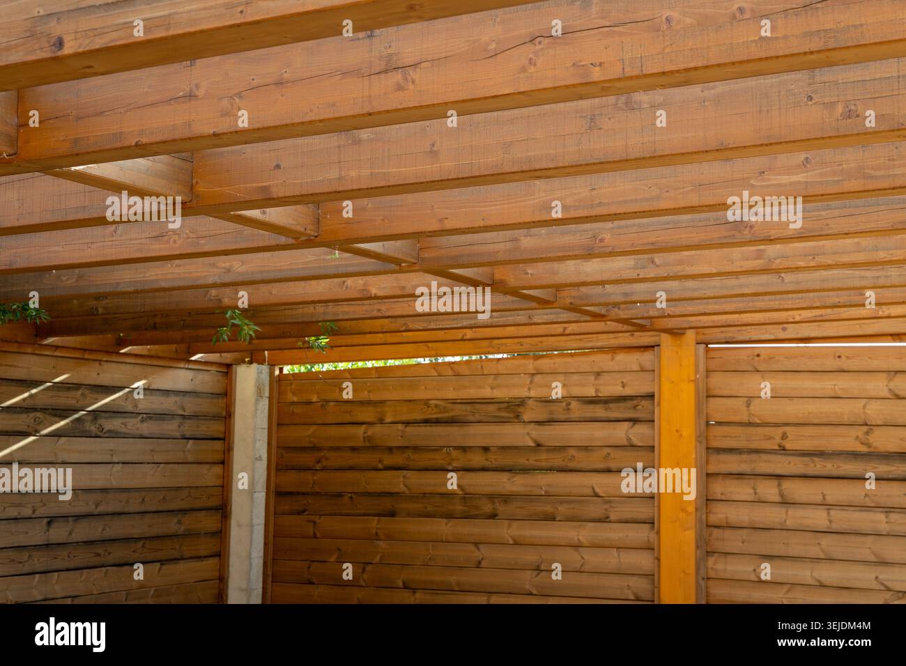 Le motif complexe de poutres en bois au-dessus complète les lignes horizontales de la clôture à lattes ci-dessous, formant un charmant abri extérieur Banque D'Images