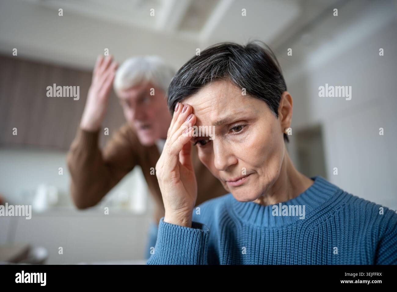 Femme triste se refermant dans la détresse tout en évitant la rage narcissique du mari et l'agression verbale Banque D'Images