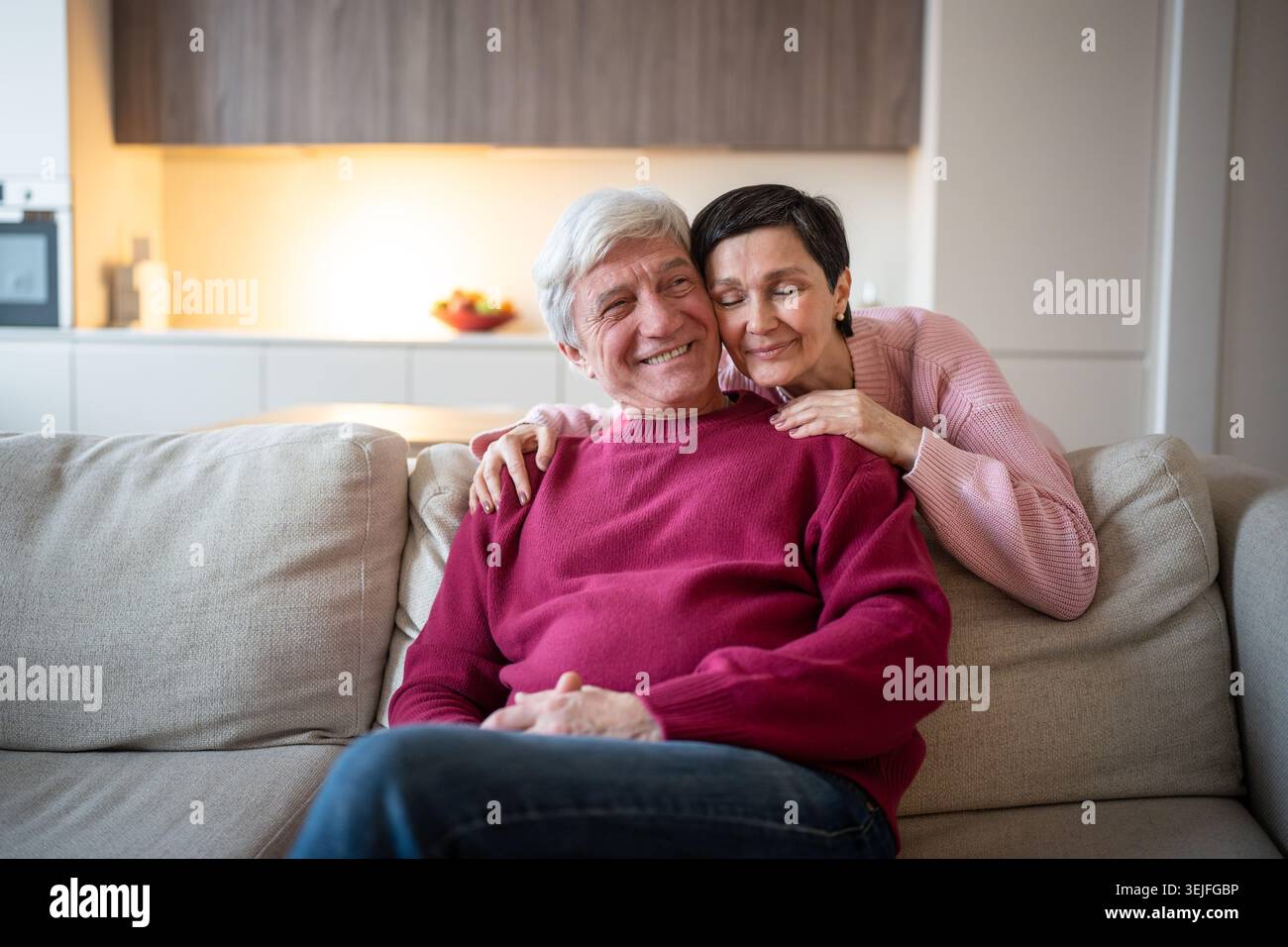 Affectueux vieux couple câlin sur le canapé à la maison, s'amuser et se reposer ensemble. Liens familiaux seniors Banque D'Images
