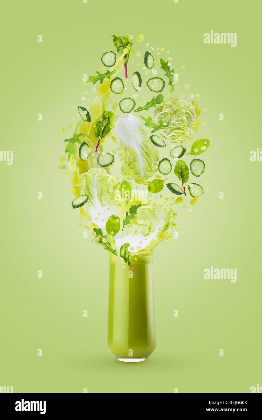 Smoothie de légumes verts frais en verre avec des feuilles vertes volantes, tranches de concombre, légumes, éclaboussures éclatantes sur le dos vert Banque D'Images