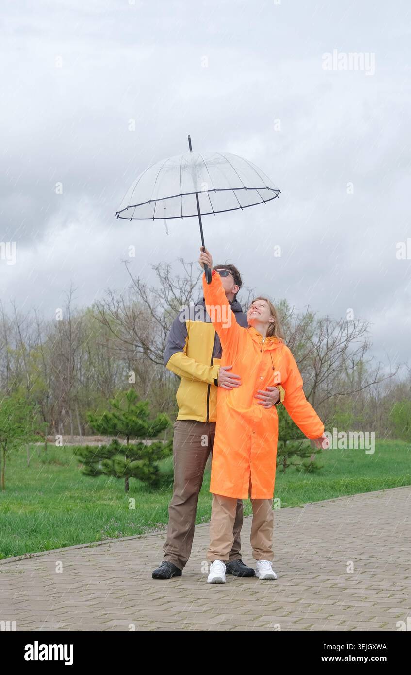 Heureux couple marchant dans le parc en jour de pluie Banque D'Images