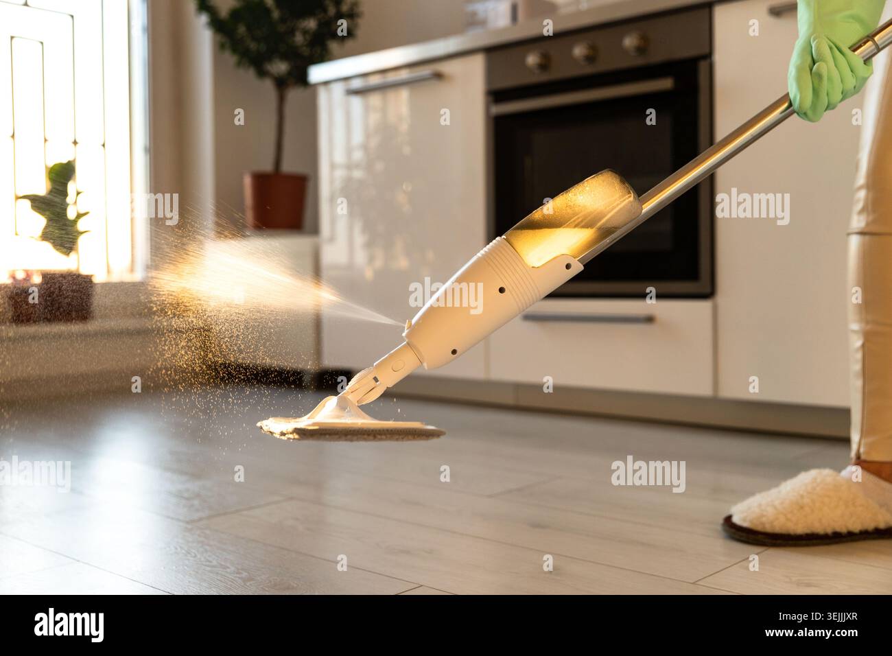Femme dans des gants en caoutchouc à l'aide d'un tampon de serpillière en microfibre et bouteille rechargeable avec solution de nettoyage, serpiler le sol dans Apartme Banque D'Images