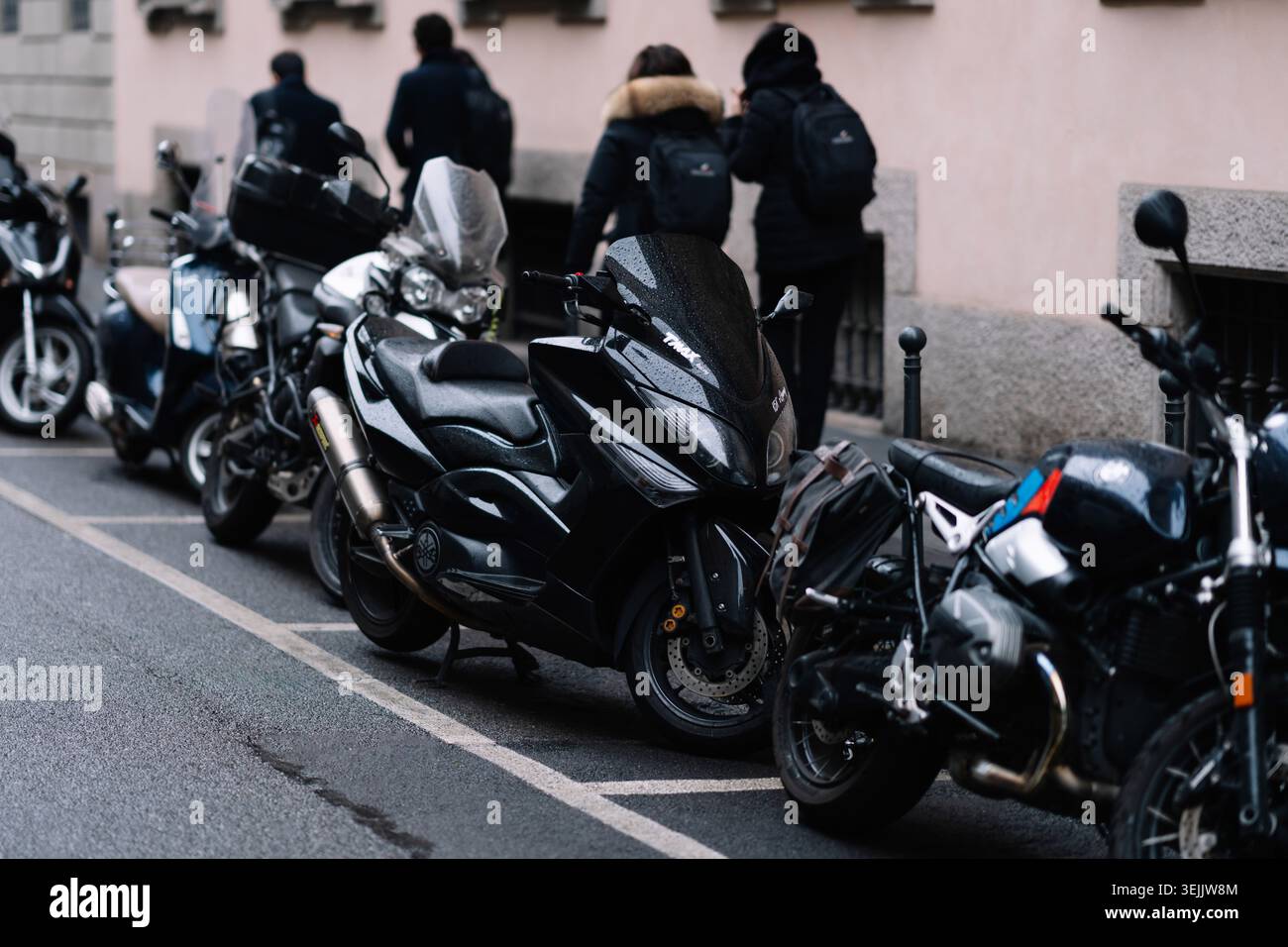 Milan, Italie - 20 janvier 2025 : rangée de motos modernes stationnées sur la rue urbaine, véhicules de transport alignés près du trottoir de la ville Banque D'Images