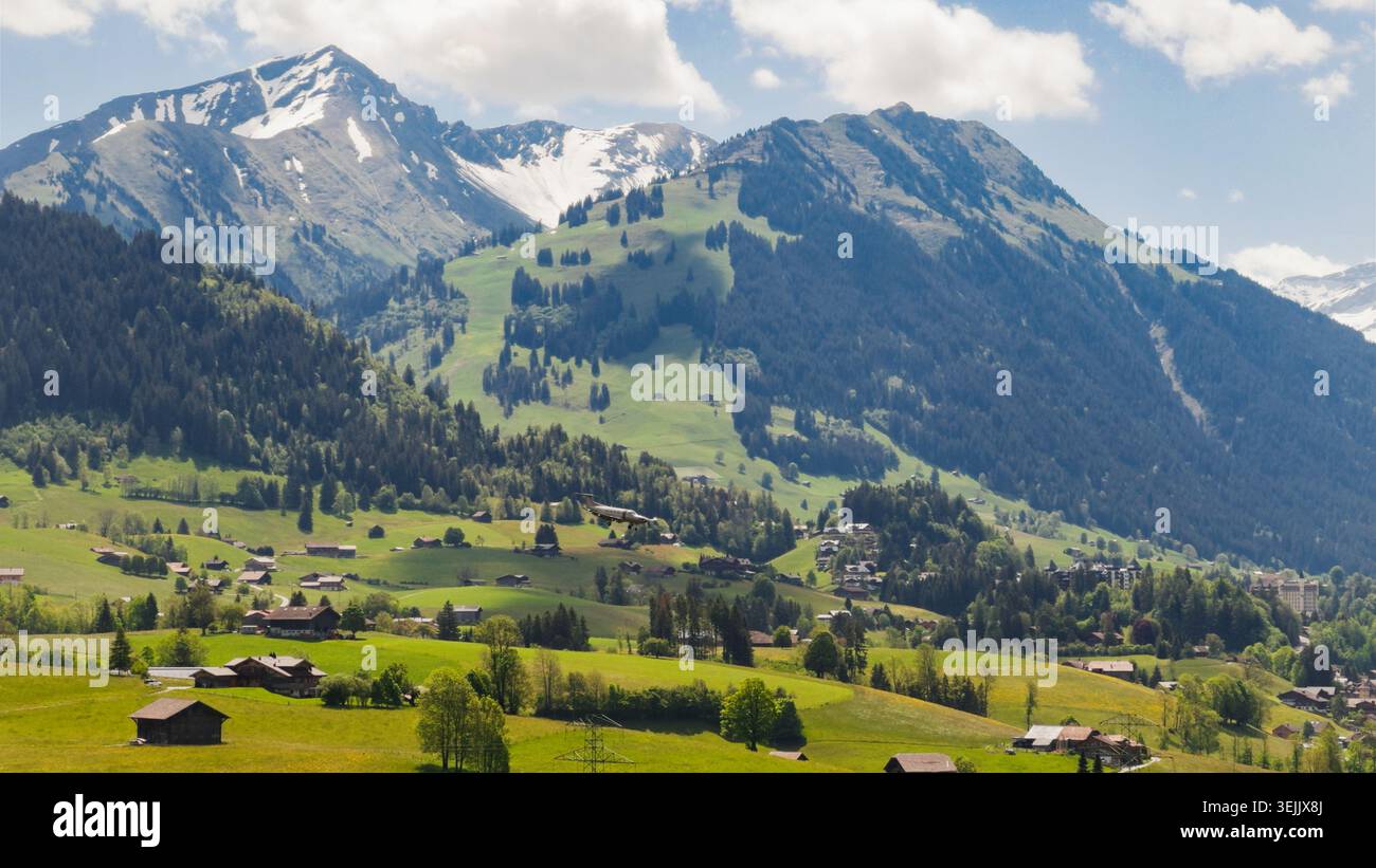 Vallée de montagne suisse présentant des chalets de village alpin et avion dans le paysage de prairie Banque D'Images