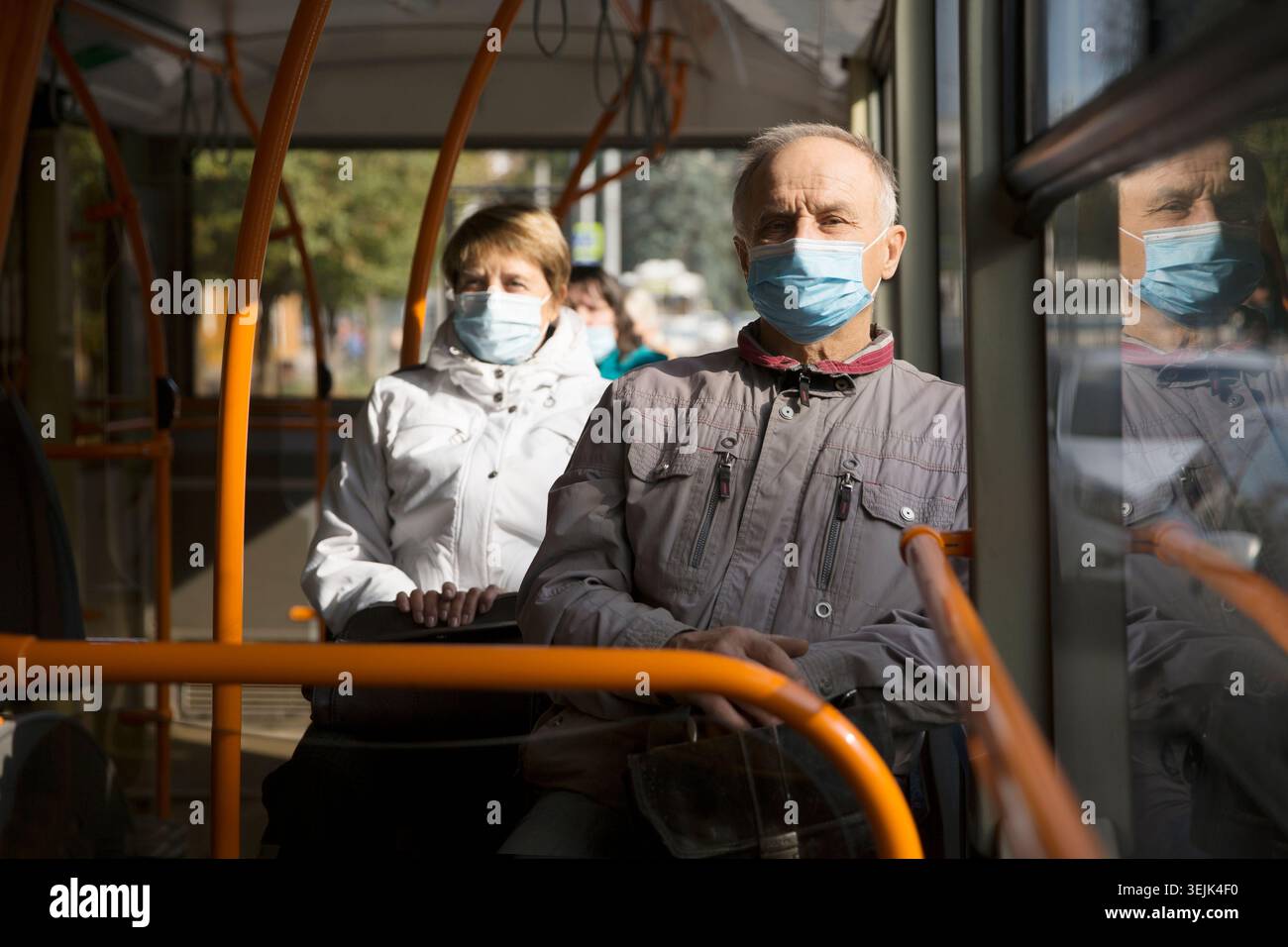 Homme senior portant un masque médical assis dans le transport en bus. Banque D'Images