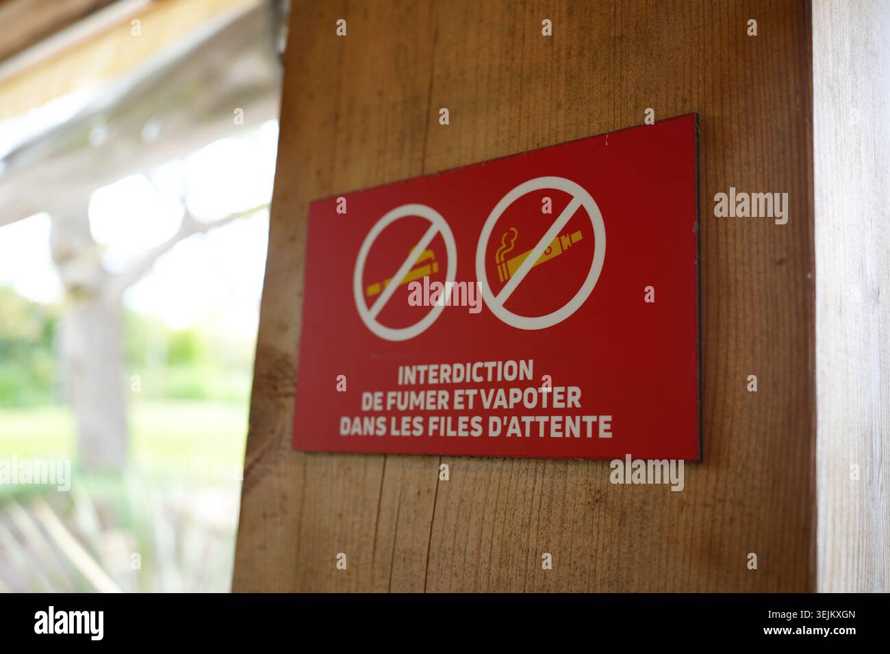Panneau non fumeur et non vapotage en français sur un poteau en bois dans une file d'attente publique. Banque D'Images