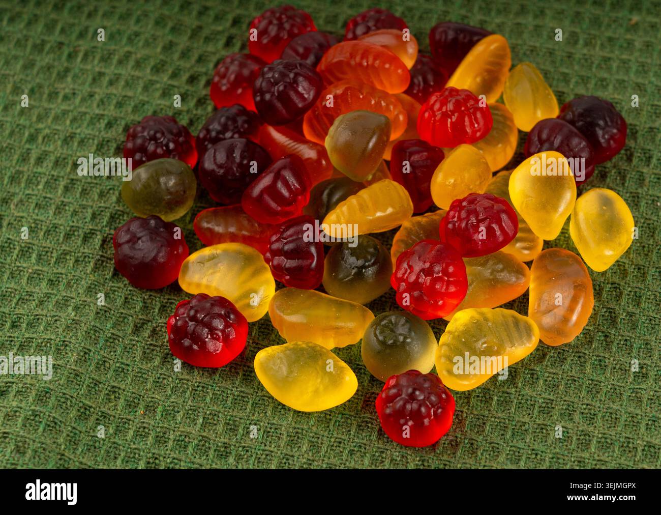 Pile de bonbons gélifiés aux fruits en gros plan, pilules de marmelade végétalienne à mâcher, tas de gumdrops de gelée, macro de bonbons en gélatine colorés sur fond vert Banque D'Images