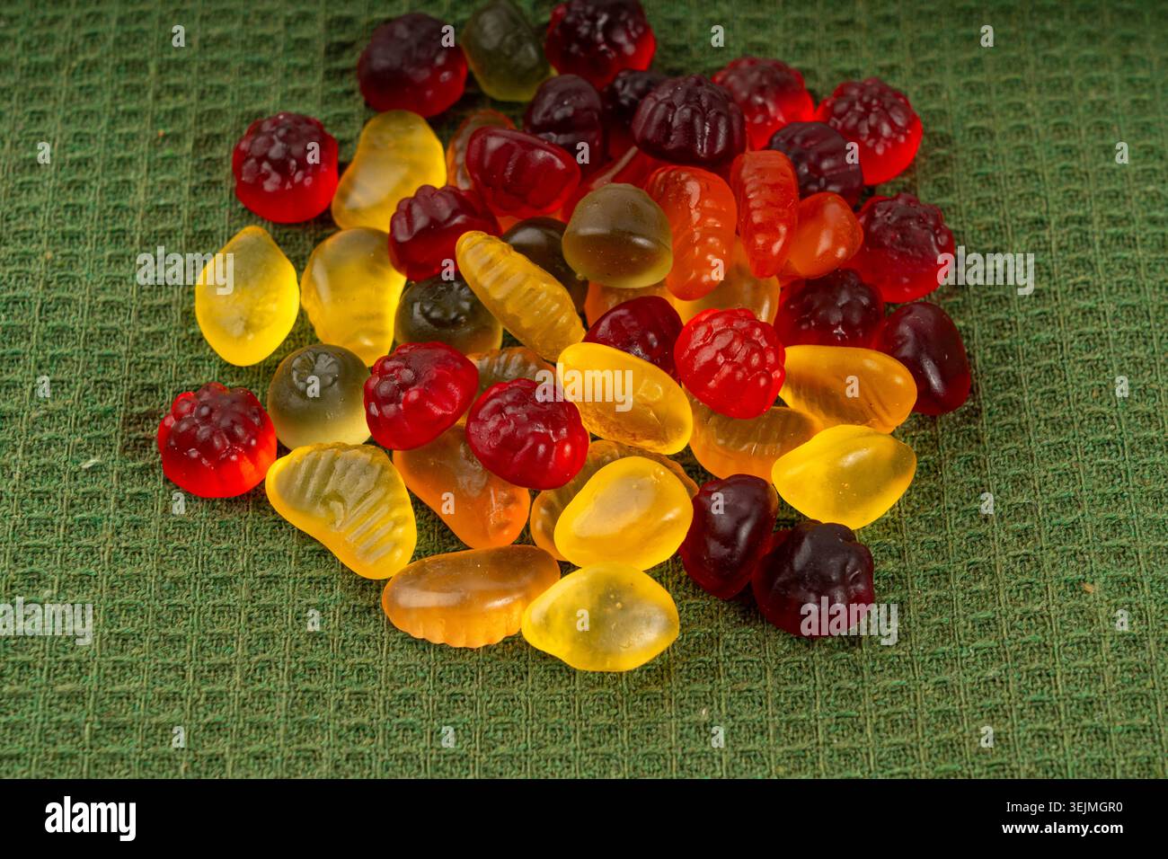 Pile de bonbons gélifiés aux fruits en gros plan, pilules de marmelade végétalienne à mâcher, tas de gumdrops de gelée, macro de bonbons en gélatine colorés sur fond vert Banque D'Images