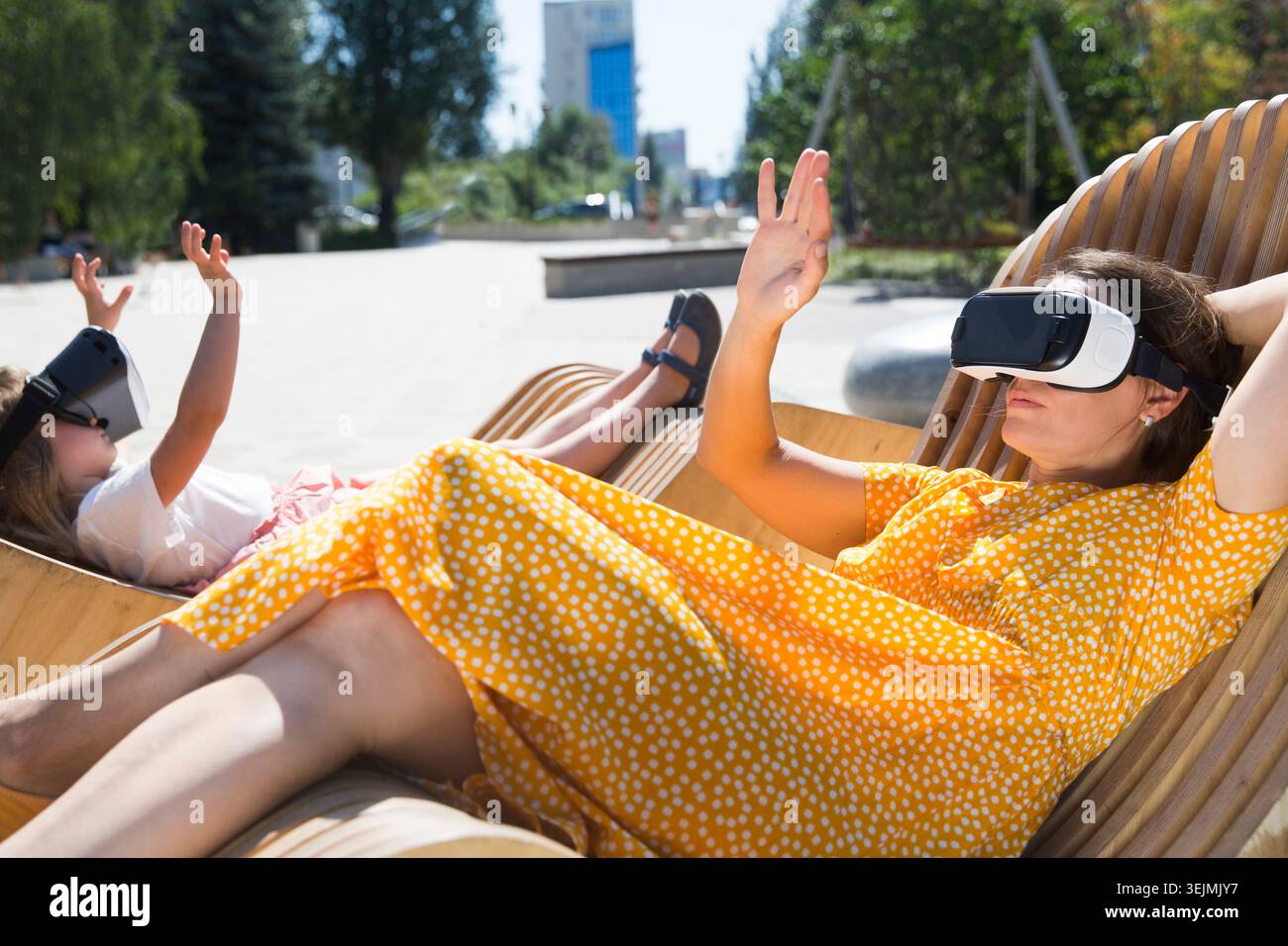Maman et fille d'enfant jouant au jeu dans des lunettes de réalité virtuelle et détendu dans la ville. copier l'espace. Concept de fami amical Banque D'Images