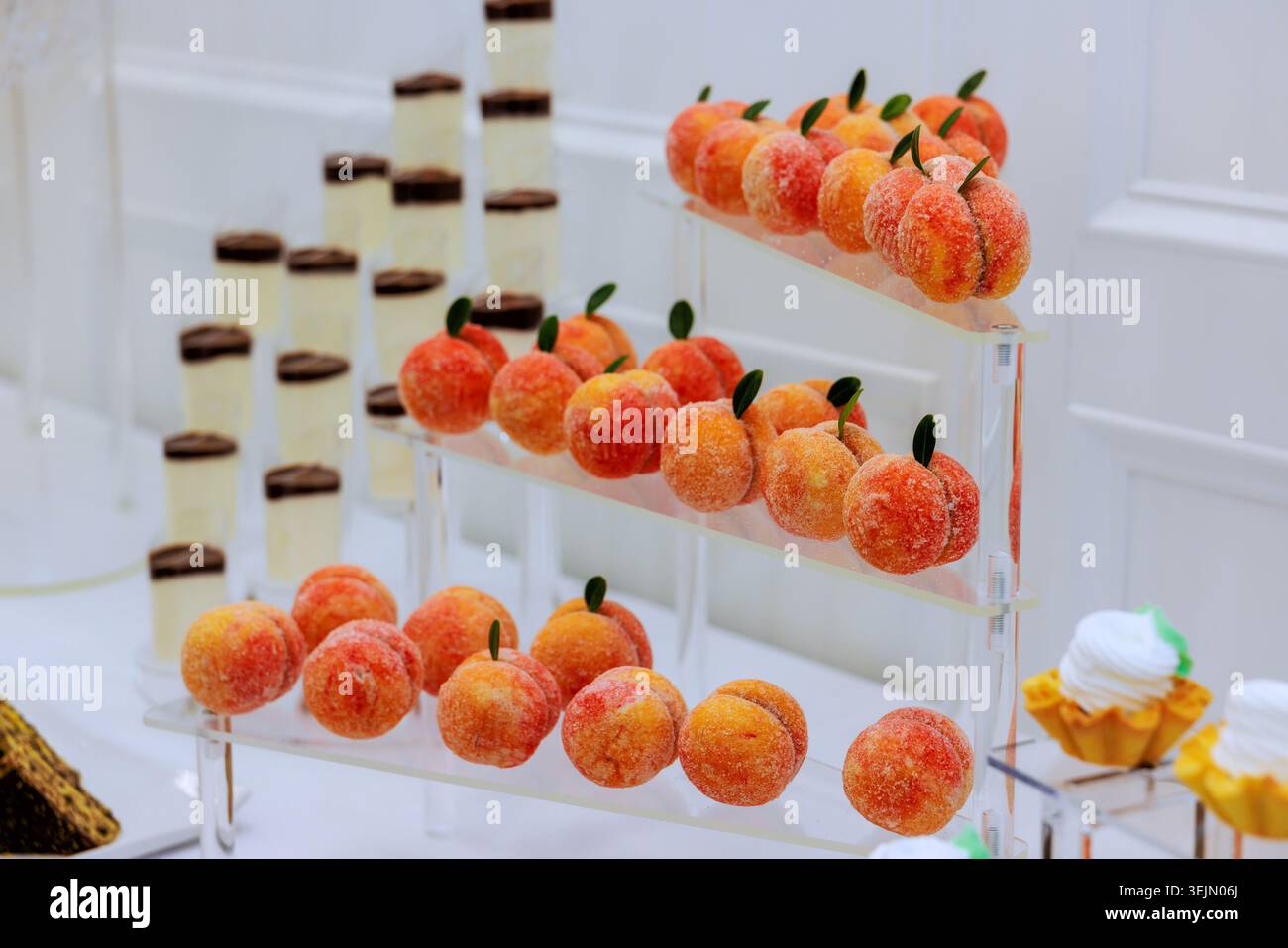 Des bonbons en forme de fruits sont disposés sur des étagères, entourés de desserts superposés lors de l'événement de mariage Banque D'Images