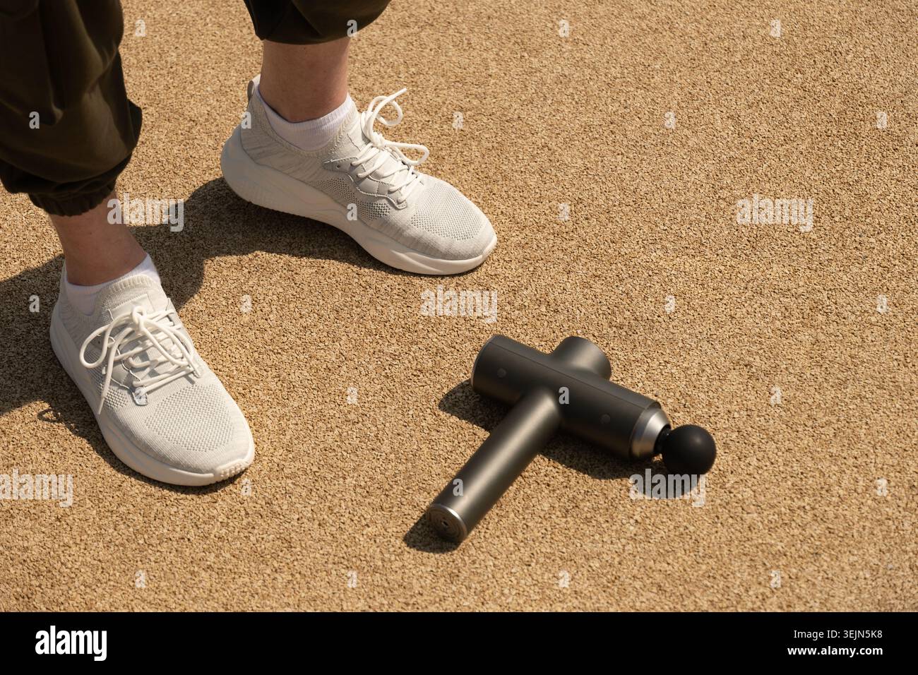 Jambes d'athlète et masseur à percussion pour réchauffer les muscles sur la zone de sport en plein air Banque D'Images