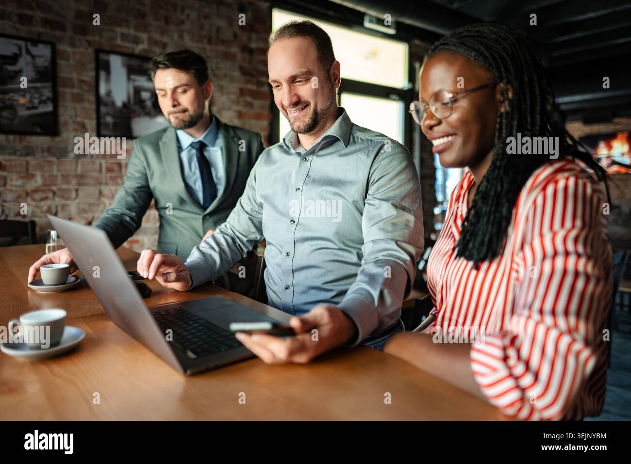 Équipe d'affaires diversifiée collaborant sur ordinateur portable dans le café Banque D'Images