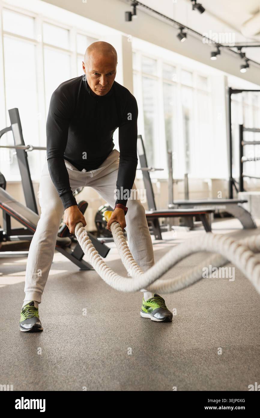 Athlète homme faire des cordes de combat exercice au gymnase. Banque D'Images