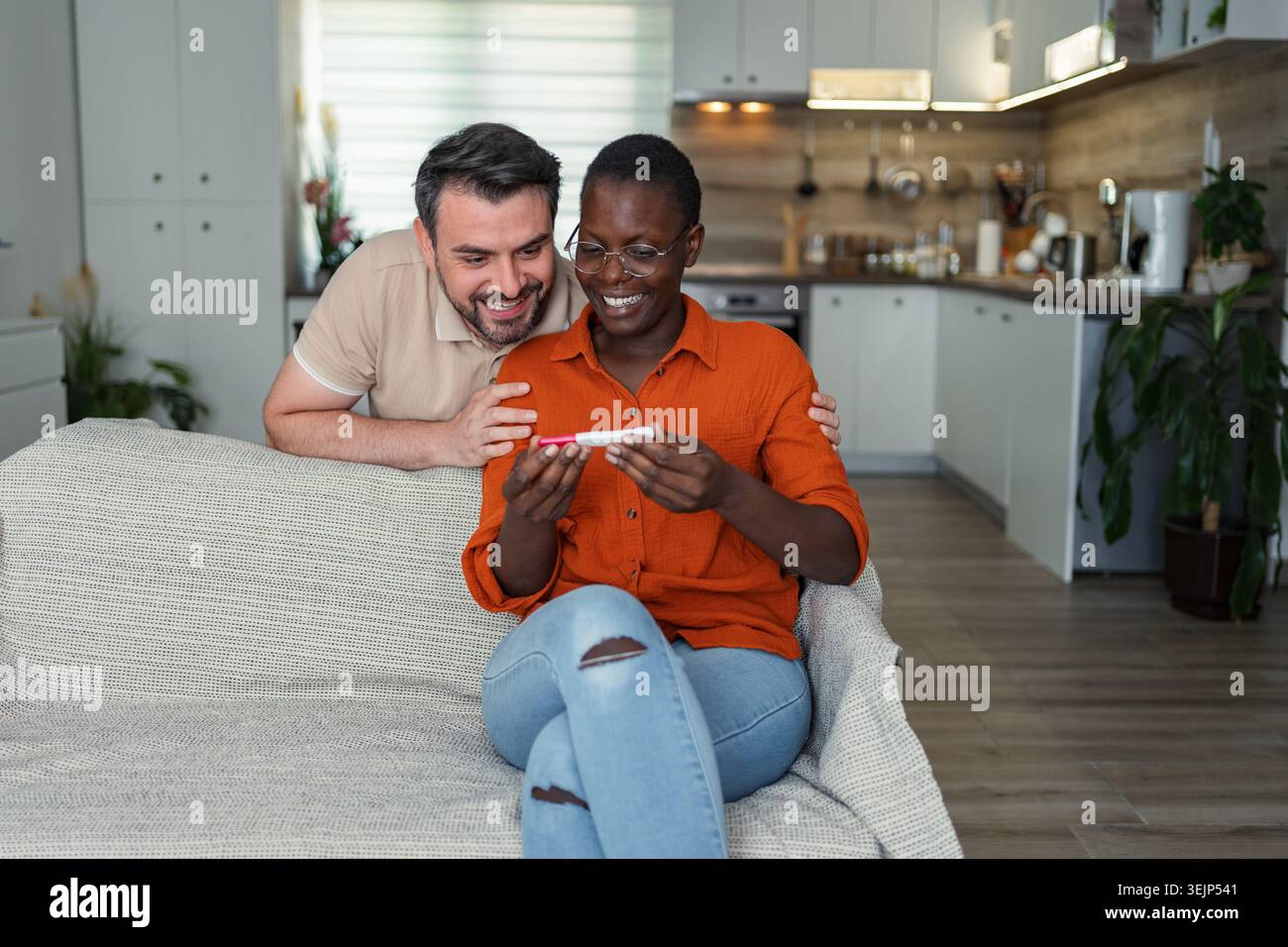 Couple interracial heureux regardant le résultat positif du test de grossesse Banque D'Images