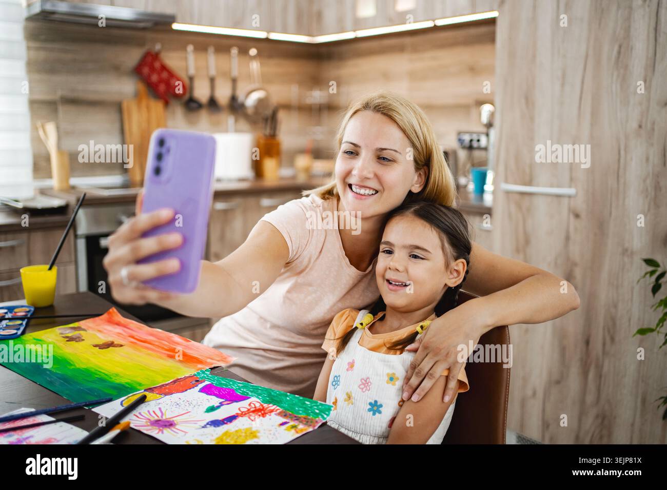 Mère et fille appréciant le temps d'art ensemble tout en prenant un selfie dans leur cuisine lumineuse Banque D'Images