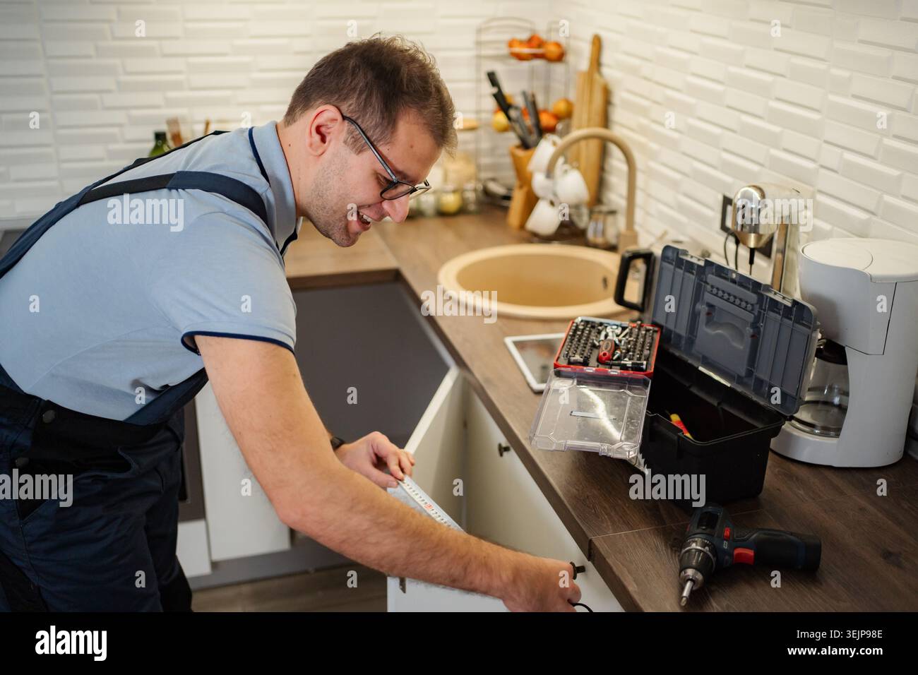Homme mesurant armoire de cuisine pour réparation et rénovation Banque D'Images